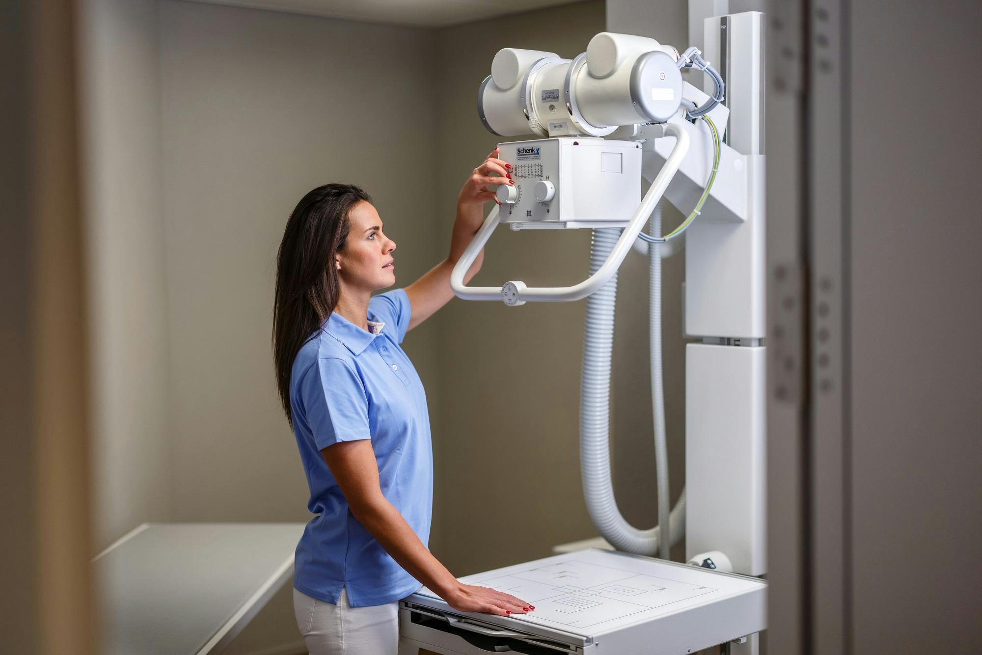 Frau bedient Röntgengerät in medizinischer Einrichtung.